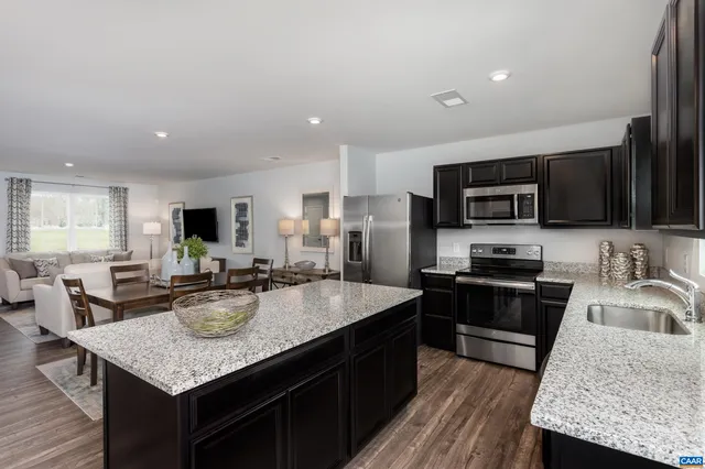a kitchen with sink a microwave refrigerator and stove top oven with wooden floor