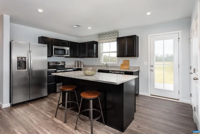 a kitchen with stainless steel appliances granite countertop a sink a stove a microwave a refrigerator and island