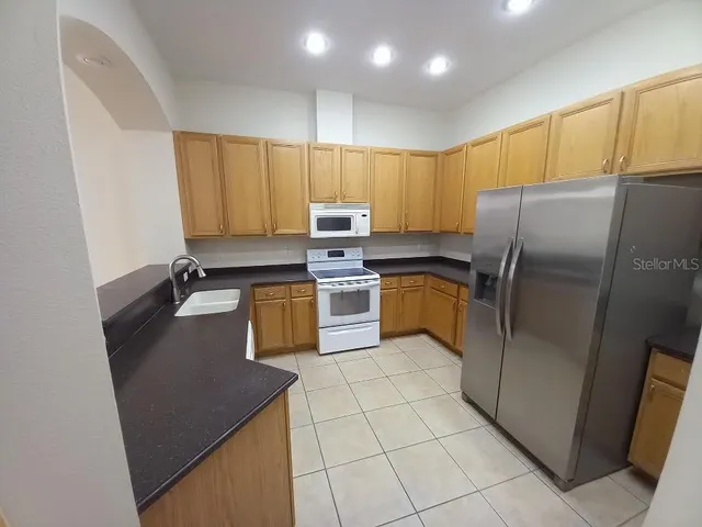 a kitchen with stainless steel appliances granite countertop a refrigerator a stove a sink and a microwave