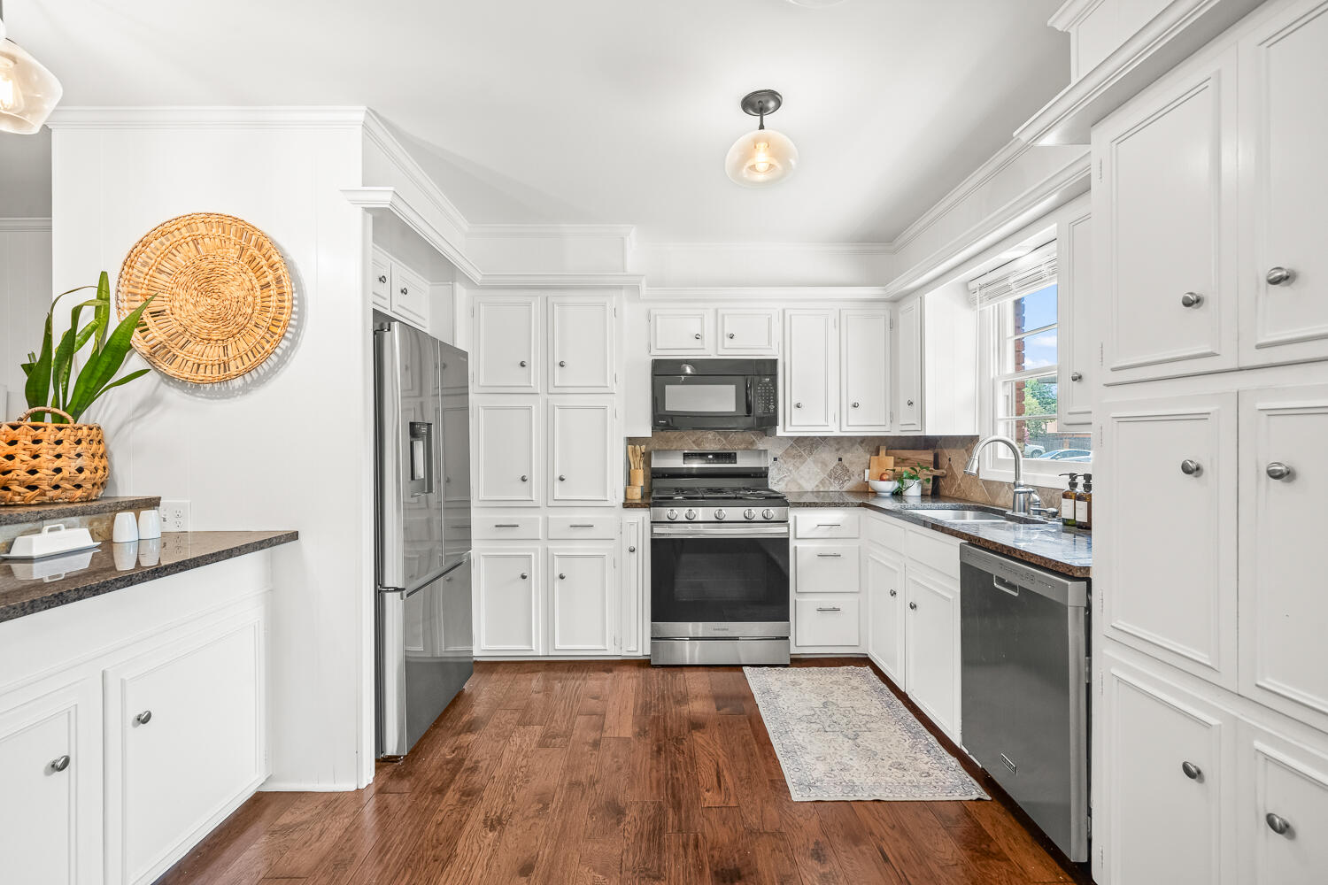 3418 62nd Street Lubbock, TX 79413 - Photo 10 of 45 a kitchen with stainless steel appliances granite countertop a refrigerator a stove and white cabinets with wooden floor