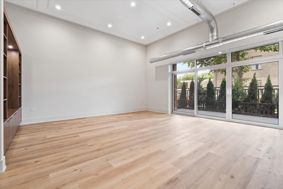 3951 North Wayne Avenue, Unit 304 Chicago, IL 60613 - Photo 8 of 20 a view of an empty room with wooden floor and a sliding door