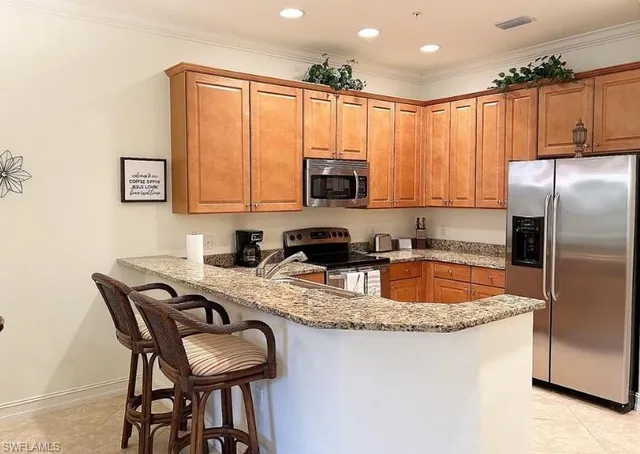 a kitchen with stainless steel appliances granite countertop a refrigerator a stove a sink and a microwave