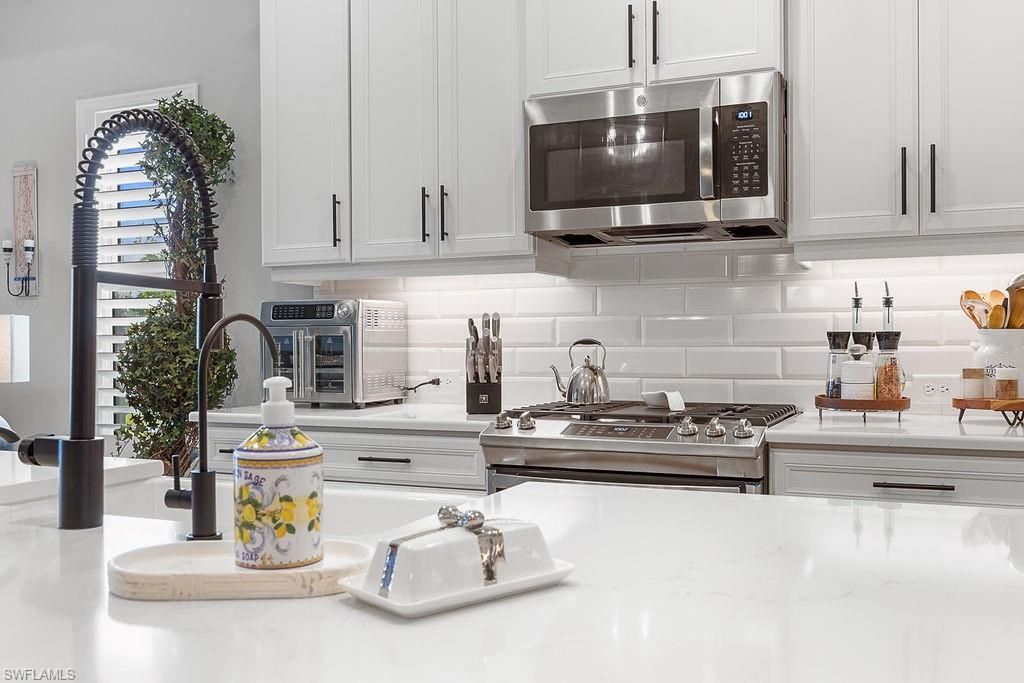 4584 Centaurus Circle Naples, FL 34120 - Photo 14 of 40 Kitchen featuring appliances with stainless steel finishes, backsplash, and white cabinets