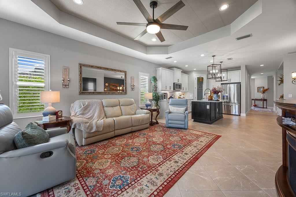 4584 Centaurus Circle Naples, FL 34120 - Photo 21 of 40 Living room featuring a raised ceiling, ceiling fan, recessed lighting, a chandelier, and light tile patterned flooring