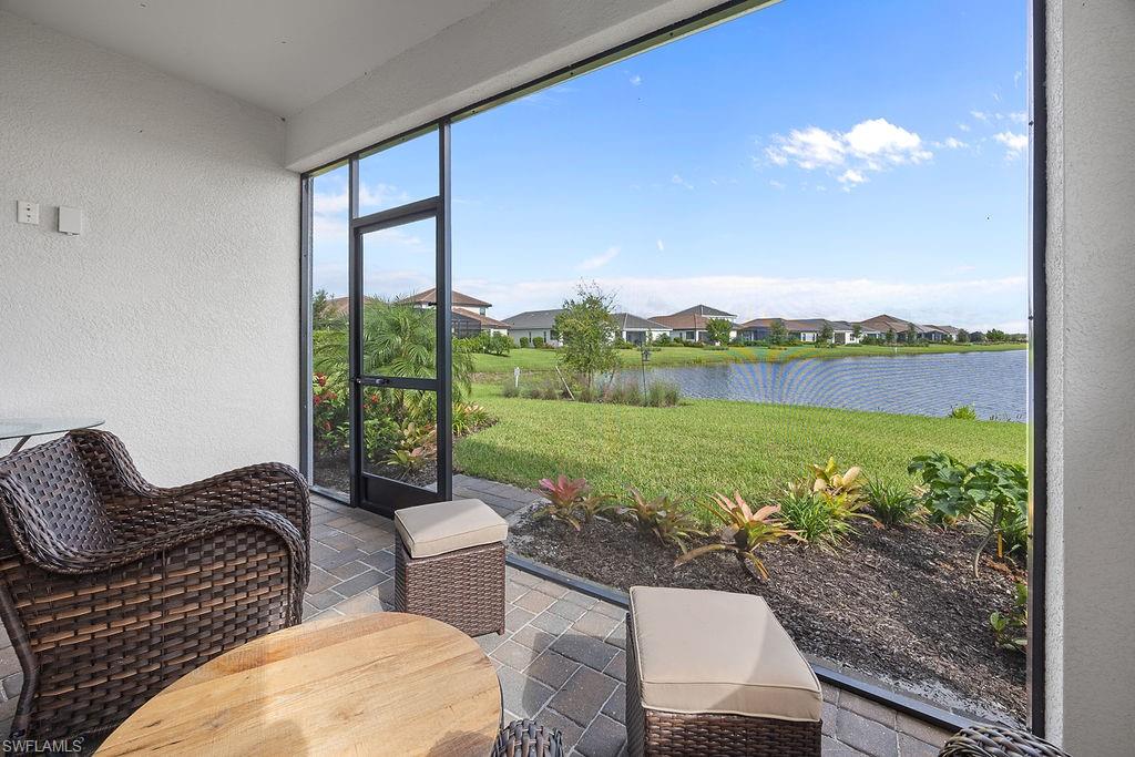 4584 Centaurus Circle Naples, FL 34120 - Photo 28 of 40 Sunroom with a textured wall, stone tile floors, a residential view, and a water view