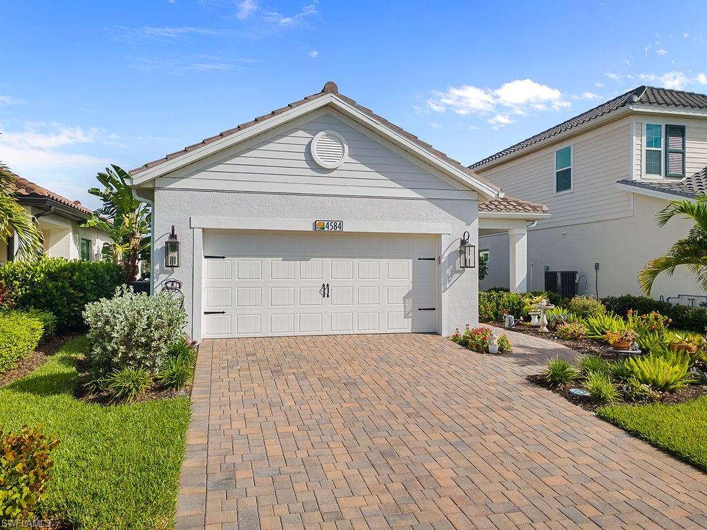 4584 Centaurus Circle Naples, FL 34120 - Photo 30 of 40 View of front of house featuring decorative driveway, an attached garage, and stucco siding