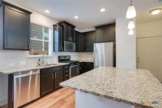 a kitchen with stainless steel appliances granite countertop refrigerator sink stove and microwave