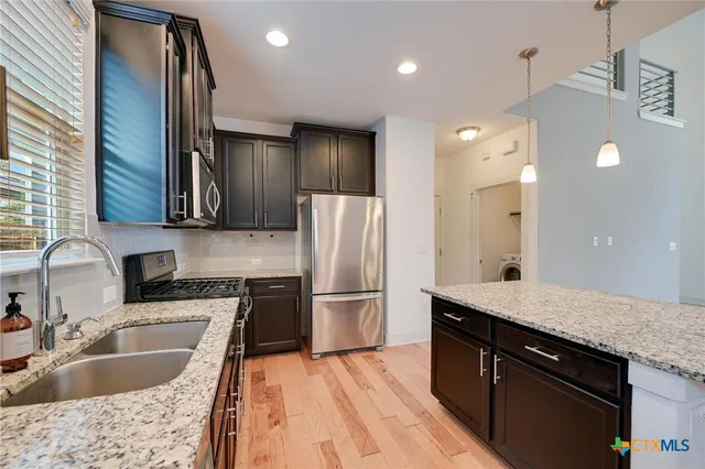 a kitchen with kitchen island granite countertop a sink stainless steel appliances and cabinets