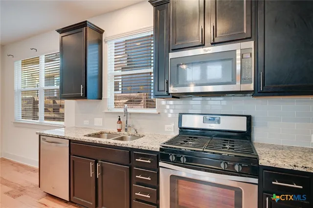a kitchen with granite countertop cabinets stainless steel appliances and a sink