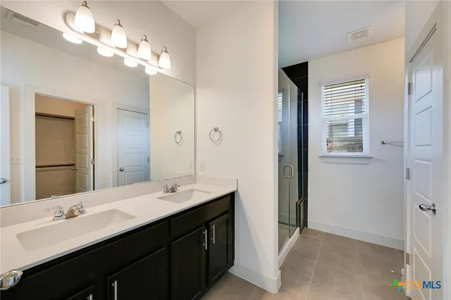 a bathroom with a double vanity sink a large mirror and a shower