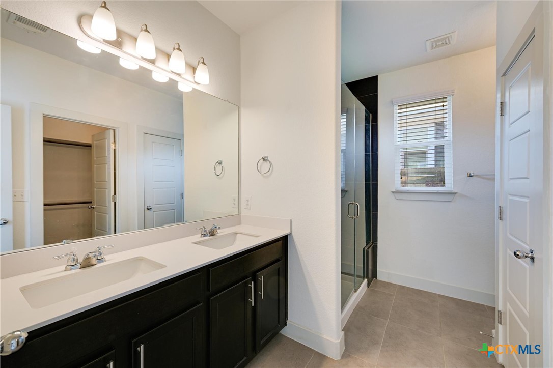 2205 Capulet Street Austin, TX 78741 - Photo 4 of 22 a bathroom with a double vanity sink a large mirror and a shower