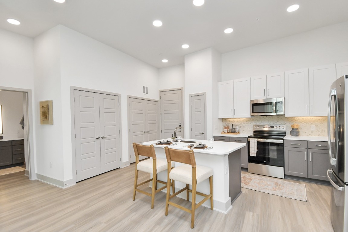 1617 Enid Street, Unit 177 Houston, TX 77009 - Photo 2 of 50 a kitchen with stainless steel appliances kitchen island granite countertop a stove top oven a sink dishwasher and a refrigerator with wooden floor