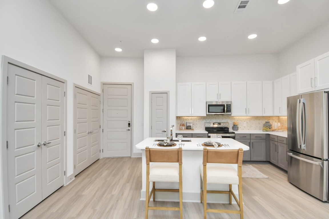 1617 Enid Street, Unit 177 Houston, TX 77009 - Photo 7 of 50 a kitchen with stainless steel appliances a refrigerator a stove top oven a sink dishwasher and white cabinets with wooden floor
