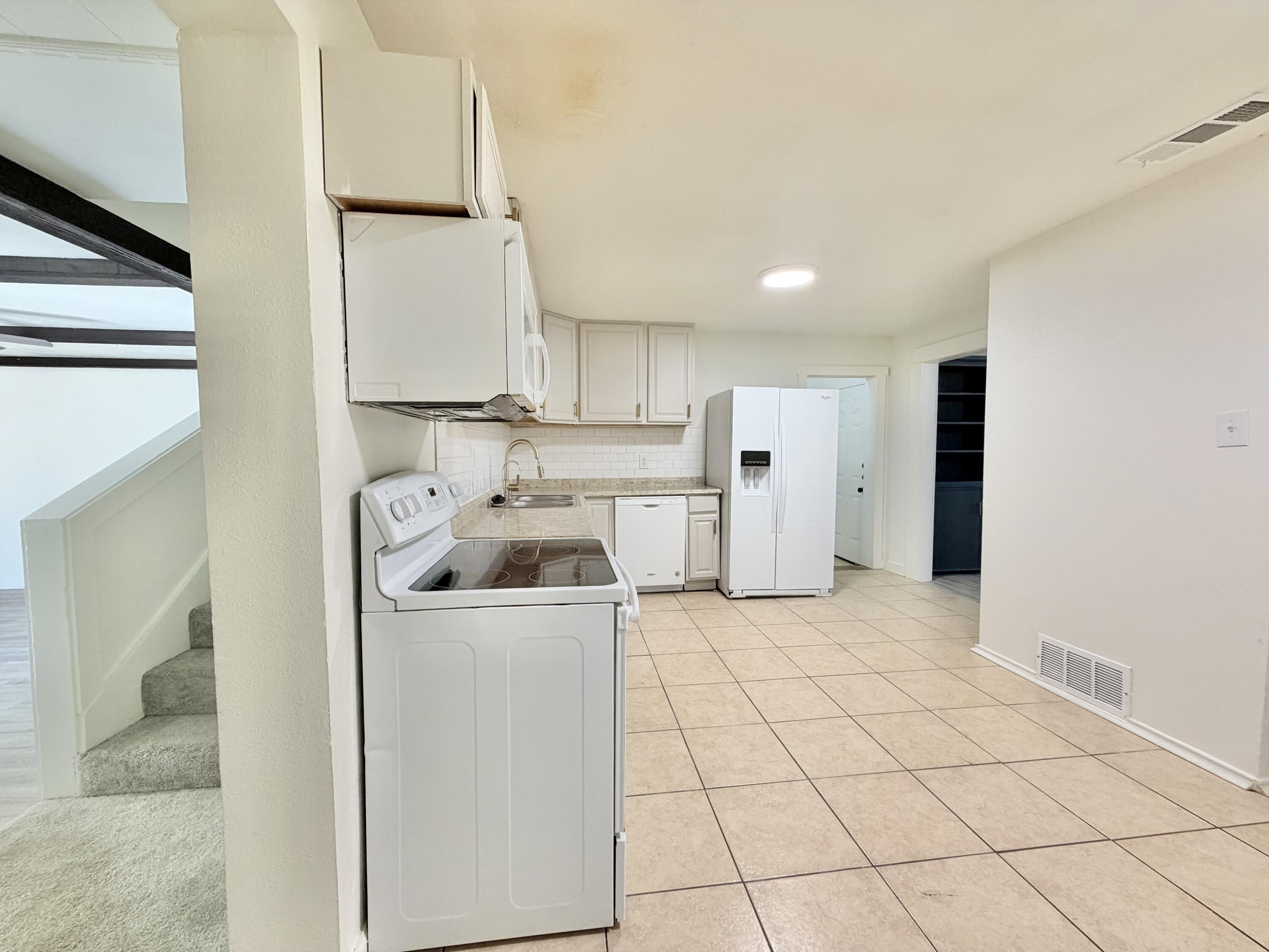 3407 30th Street Lubbock, TX 79410 - Photo 7 of 26 a kitchen with a sink a refrigerator and cabinets
