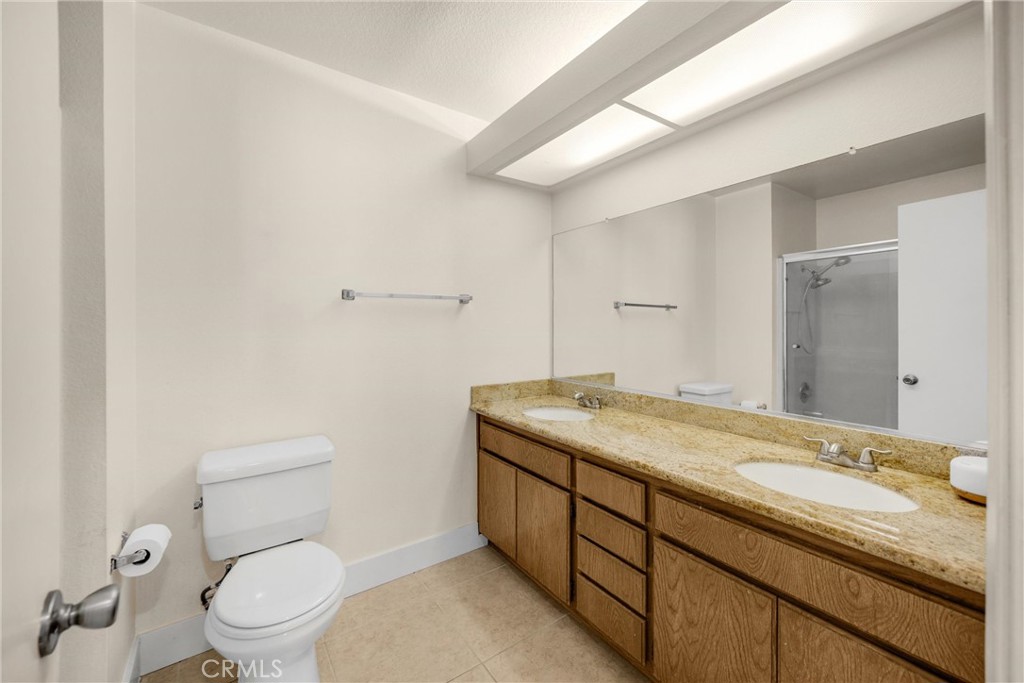 7077 Campbell Place Rancho Cucamonga, CA 91701 - Photo 28 of 74 a bathroom with a granite countertop sink a toilet and a mirror
