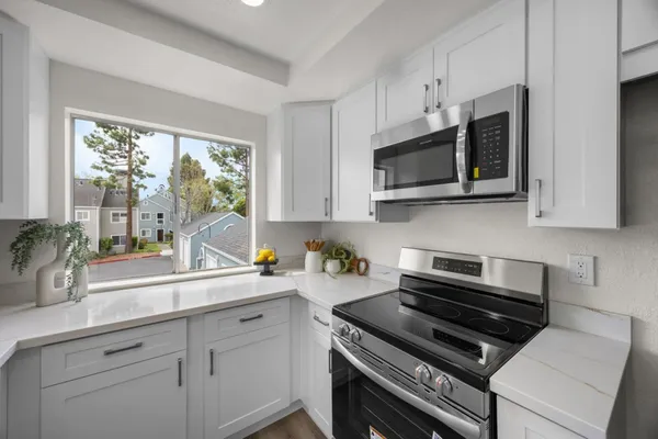 a kitchen with appliances a sink a window and cabinets
