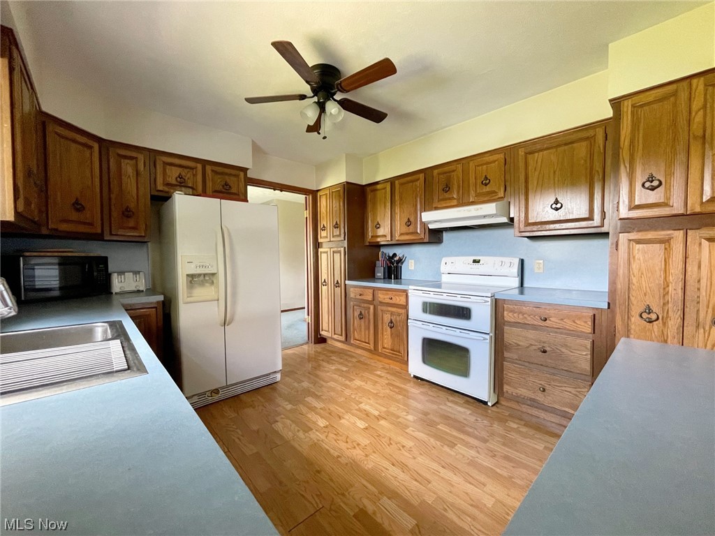 15508 West Calla Road Beloit, OH 44609 - Photo 4 of 19 Kitchen featuring ceiling fan, brown cabinets, white appliances, and light hardwood flooring