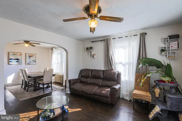 a living room with furniture a flat screen tv and a refrigerator
