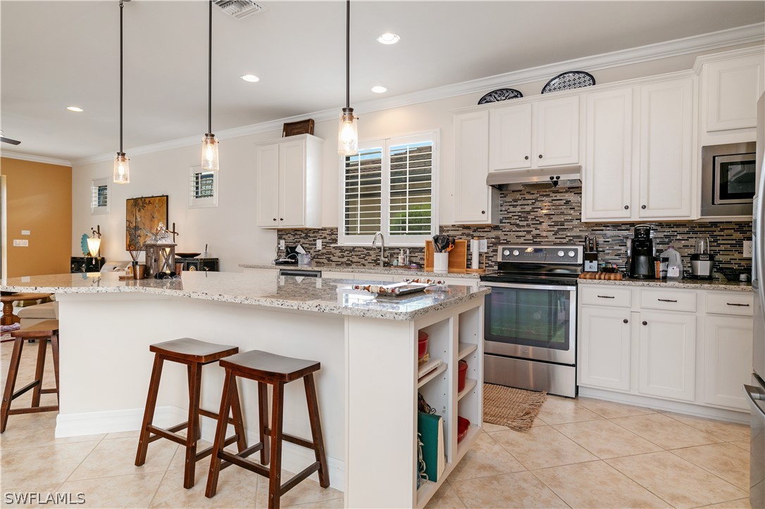 10922 Dennington Road Fort Myers, FL 33913 - Photo 13 of 35 a kitchen with stainless steel appliances a sink a stove a refrigerator cabinets and chairs