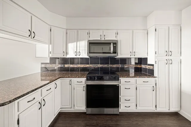 a view of an empty room with wooden floor and a ceiling fan