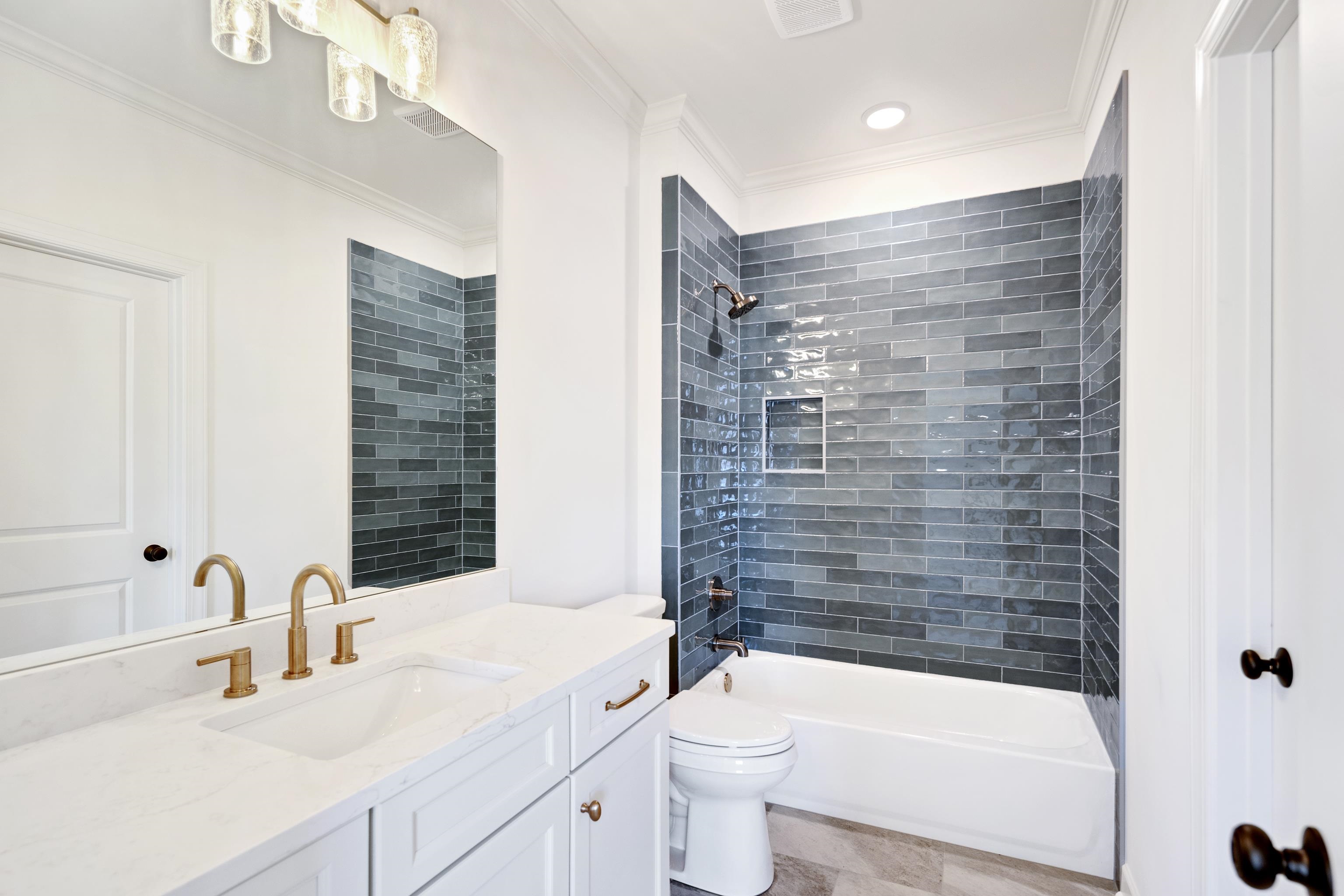 3406 Village Cross Loop Collierville, TN 38017 - Photo 33 of 40 White vanity with gold-finish fixtures and an integrated sink, large rectangular mirror, and a tile shower surround with a built-in niche