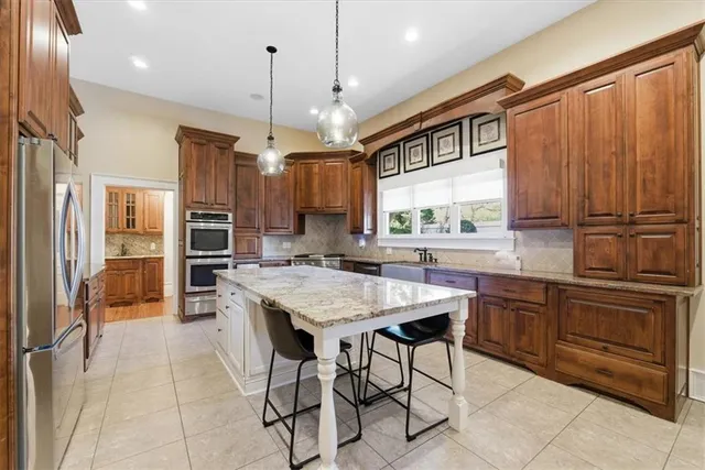 a kitchen with stainless steel appliances granite countertop table chairs stove refrigerator and cabinets