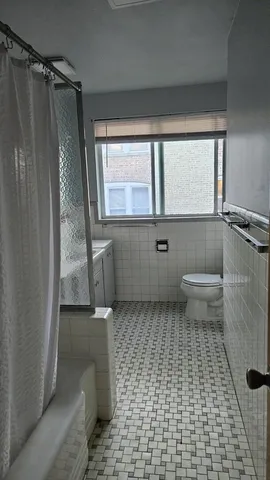 a bathroom with a toilet a window and shower