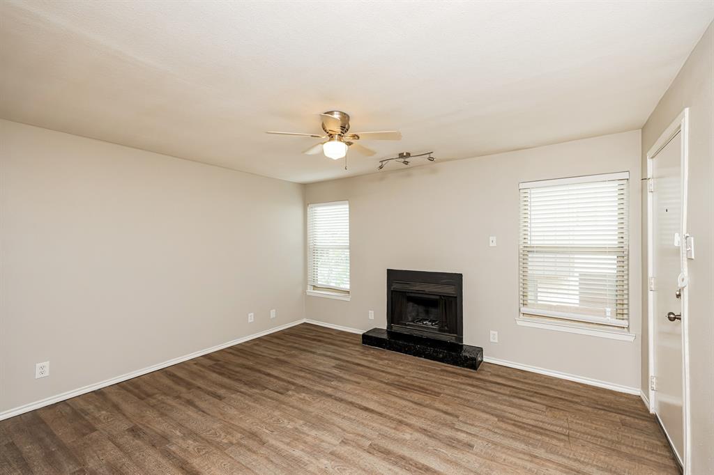 4622 Monarch Street, Unit 202 Dallas, TX 75204 - Photo 4 of 16 Living area featuring wood-finish flooring, a black hearth fireplace, and a ceiling fan with integrated lighting