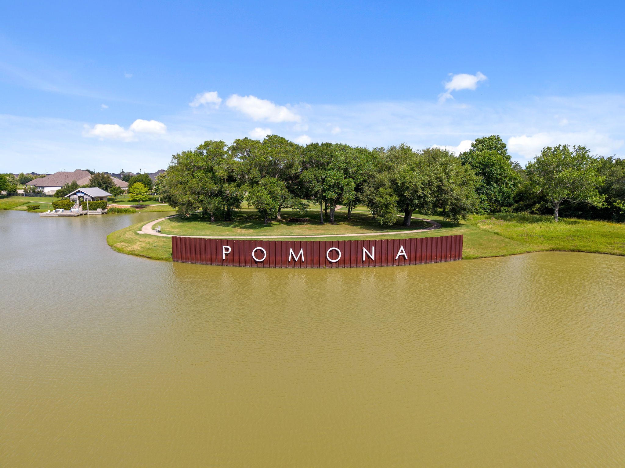 2119 Blackhawk Ridge Lane Manvel, TX 77578 - Photo 47 of 49 Iconic Pomona community sign reflected in the shimmering lake waters, framed by mature oak trees and scenic walking trails — a stunning landmark that embodies the beauty, lifestyle, and pride of calling Pomona home.