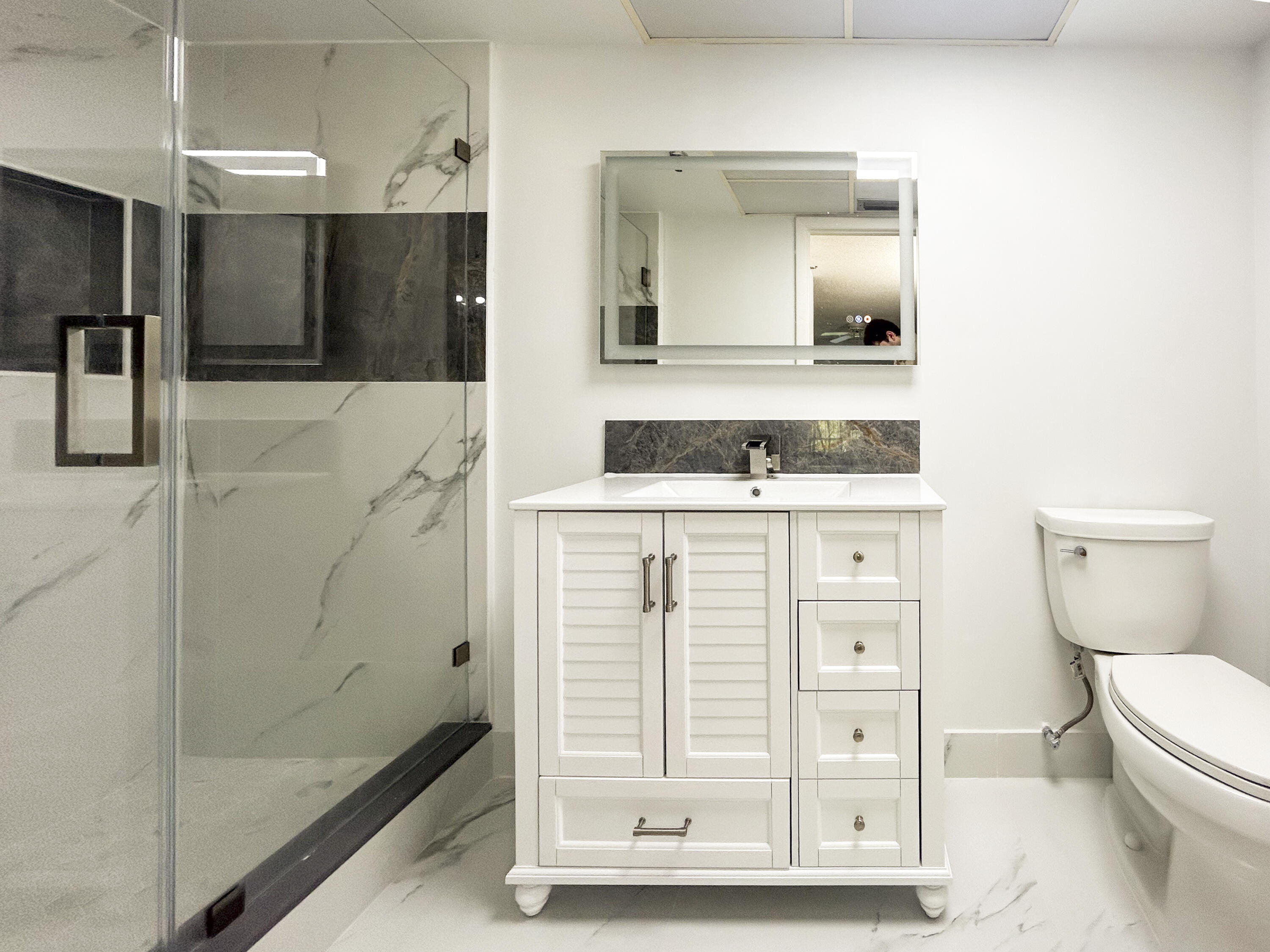 9235 Southwest 8th Street, Unit 114 Boca Raton, FL 33428 - Photo 11 of 18 a bathroom with a sink a toilet a mirror and shower