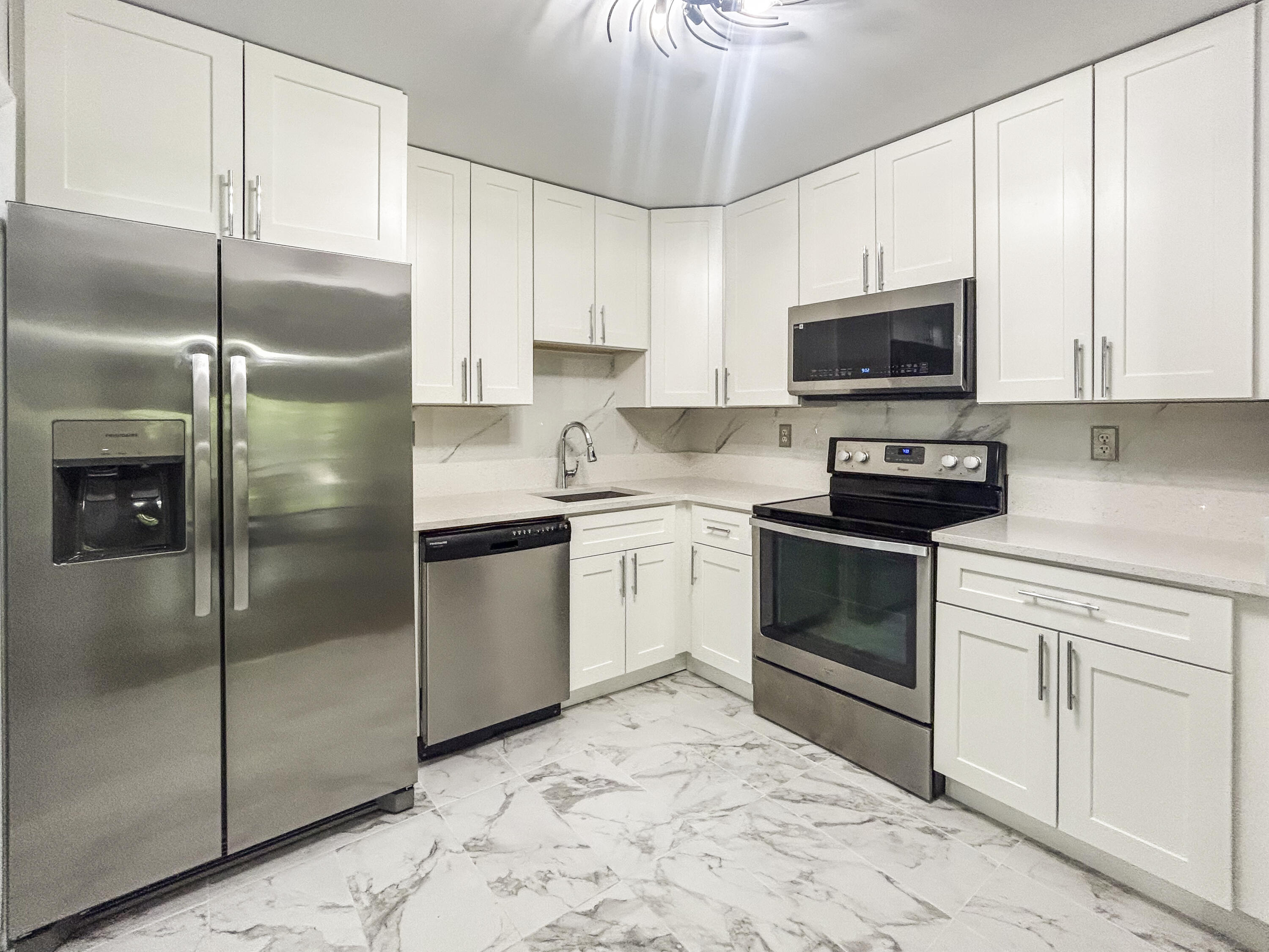 9235 Southwest 8th Street, Unit 114 Boca Raton, FL 33428 - Photo 7 of 18 a kitchen with a refrigerator stove and white cabinets