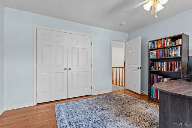 a view of an empty room with bookshelf and wooden floor