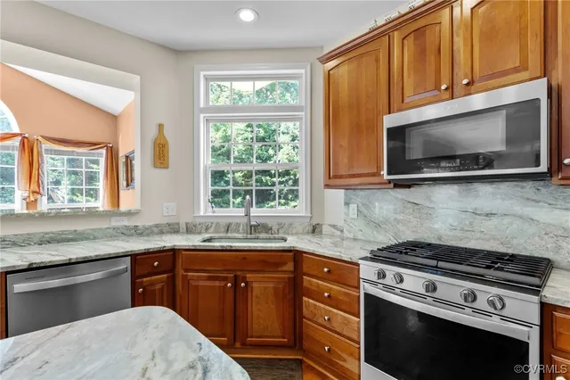 a kitchen with granite countertop cabinets stainless steel appliances a sink and window