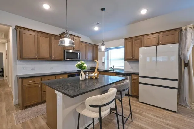 a kitchen with stainless steel appliances granite countertop a sink a refrigerator and a granite counter tops