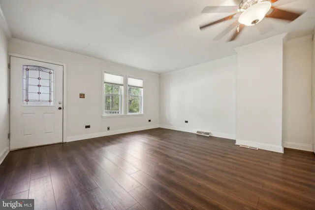 an empty room with wooden floor chandelier fan and windows