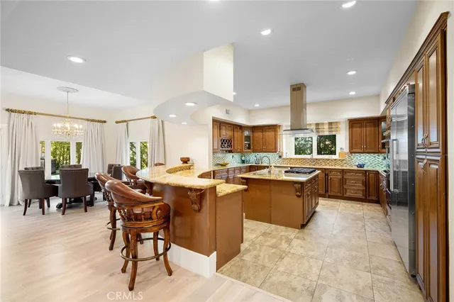 a large kitchen with kitchen island a sink a counter and chairs
