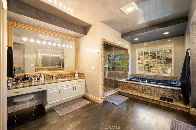 a bathroom with a sink a large mirror and a bathtub next to a window