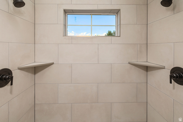 612 North 400 West Logan, UT 84321 - Photo 23 of 27 Modern shower enclosure featuring large-format rectangular tile, dual shower heads, integrated corner shelving, and oil-rubbed bronze fixtures