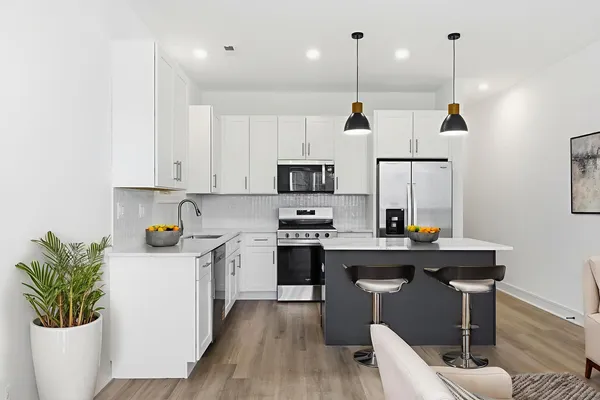 a kitchen with kitchen island white cabinets stainless steel appliances a sink and wooden floor