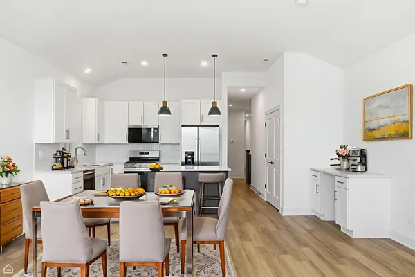 a kitchen with a dining table chairs refrigerator and microwave