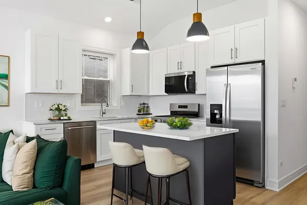 a kitchen with stainless steel appliances granite countertop a refrigerator a sink a stove a dining table and chairs