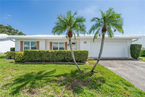 a backyard of a house with table and chairs plants and large tree
