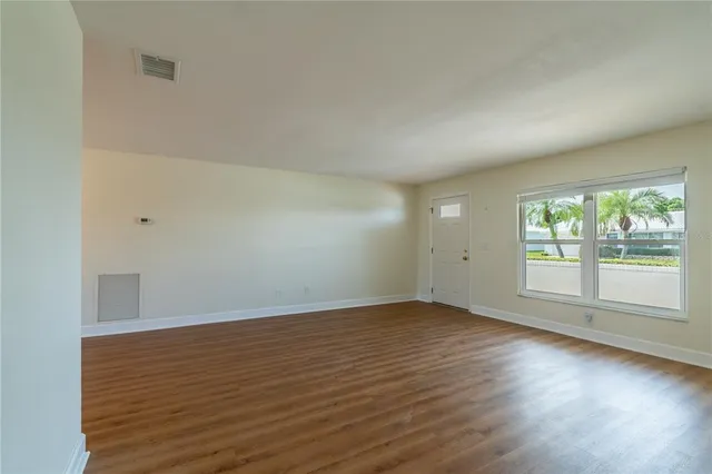 an empty room with wooden floor and windows