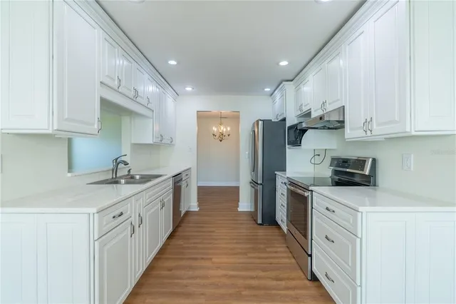 a large kitchen with stainless steel appliances granite countertop a lot of counter space and wooden floors