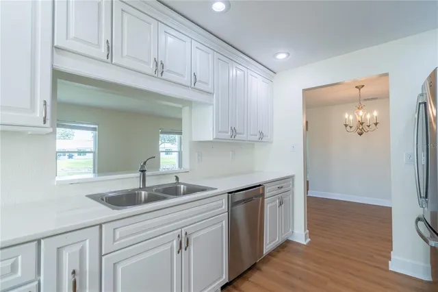 a kitchen with stainless steel appliances granite countertop a sink and cabinets with wooden floor