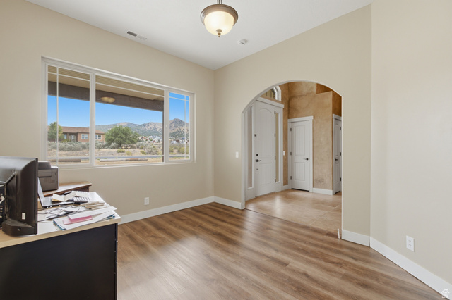 2567 West Rim Rock Drive Stockton, UT 84071 - Photo 21 of 64 Neutral-toned room featuring a large window with mountain scenery, wood-finish flooring, and an arched entryway