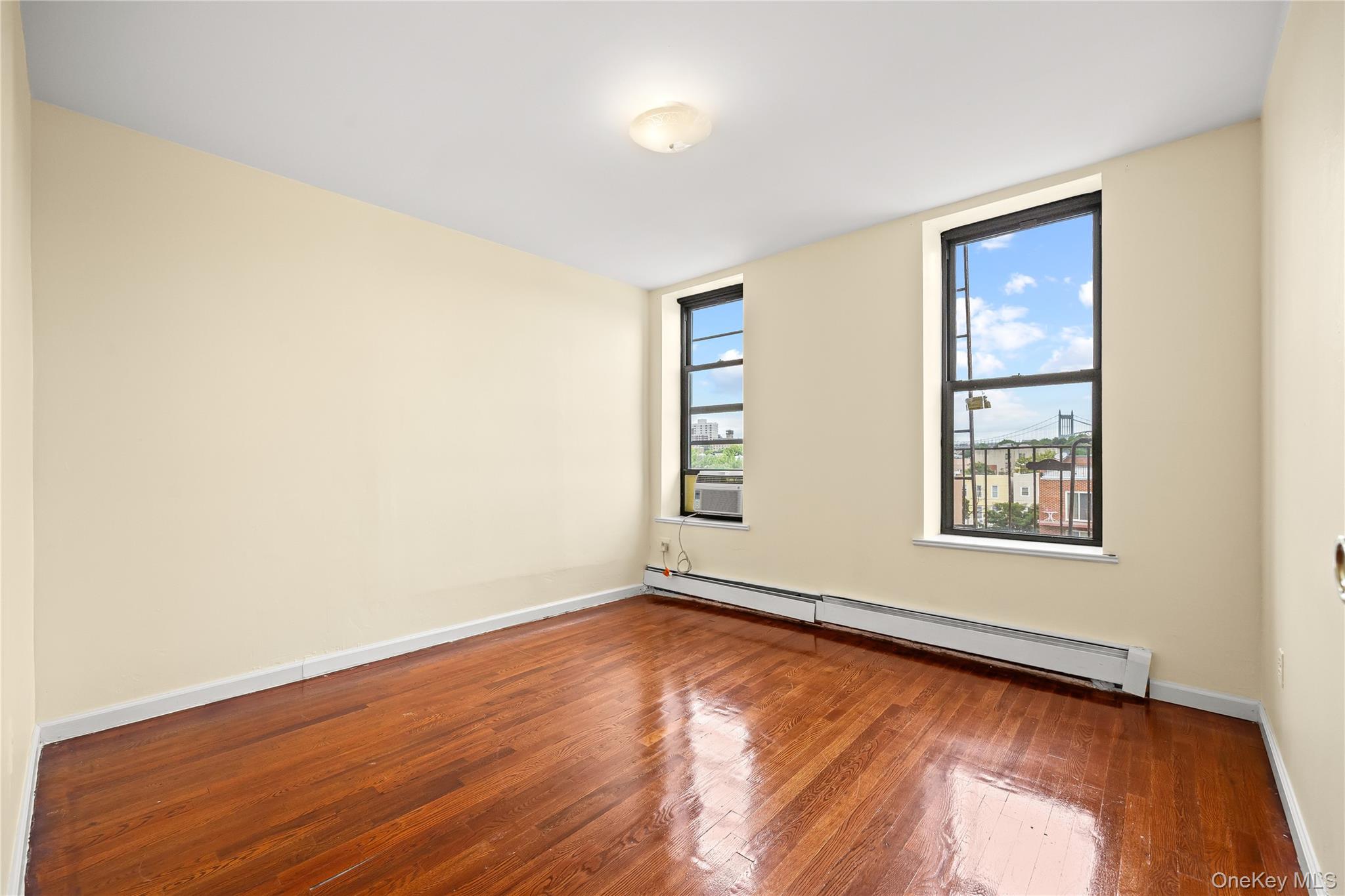 1423 31st Avenue, Unit 4E Queens, NY 11106 - Photo 9 of 23 Spare room with baseboard heating and hardwood / wood-style floors
