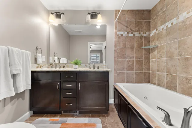 a bathroom with a double vanity sink a mirror and a bathtub