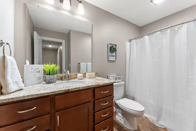 a bathroom with a granite countertop sink toilet and mirror