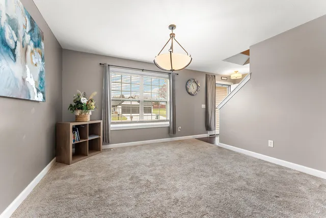 a view of an empty room with a window and kitchen view